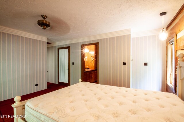 bedroom featuring a textured ceiling, ornamental molding, ensuite bath, and ceiling fan