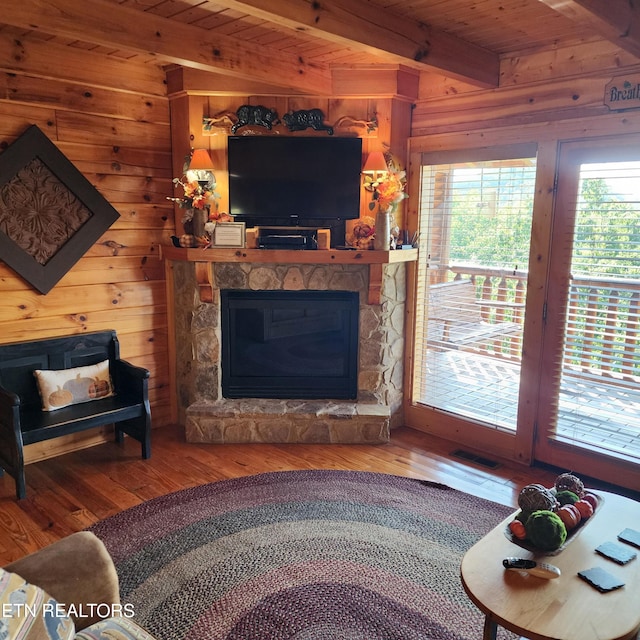 living room featuring a stone fireplace, wooden ceiling, beam ceiling, hardwood / wood-style flooring, and wooden walls