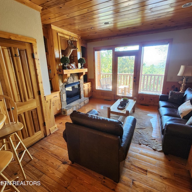 living room featuring light hardwood / wood-style flooring, wood ceiling, and a fireplace