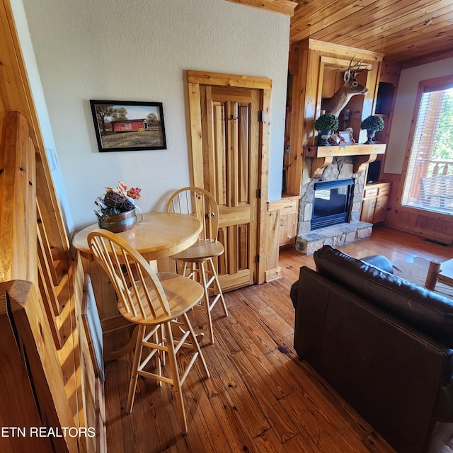 living room featuring a stone fireplace, hardwood / wood-style flooring, and wood ceiling