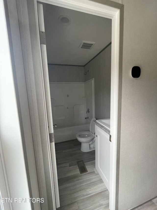 full bathroom with wood-type flooring, vanity, toilet, and washtub / shower combination