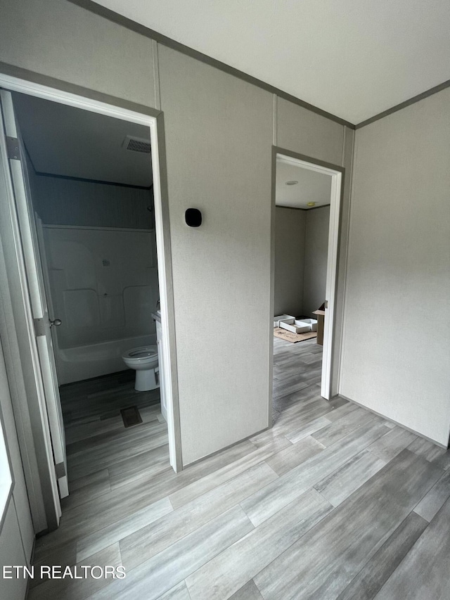 unfurnished bedroom featuring light hardwood / wood-style floors and ensuite bath