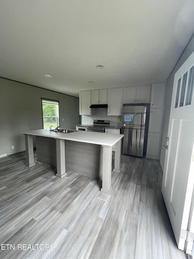 kitchen with a kitchen island with sink, range with electric cooktop, light hardwood / wood-style flooring, gray cabinetry, and stainless steel fridge