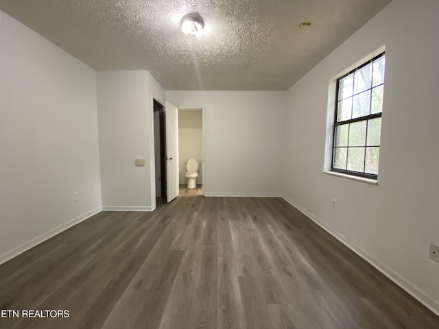 interior space featuring dark hardwood / wood-style floors, ensuite bathroom, and a textured ceiling