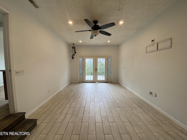 unfurnished room with french doors, a textured ceiling, light wood-type flooring, and ceiling fan