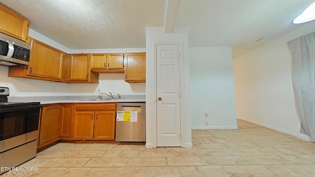 kitchen with a textured ceiling, stainless steel appliances, and sink