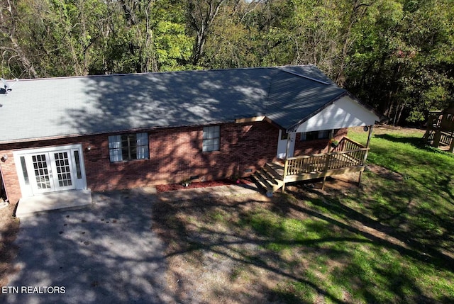 rear view of house with french doors, a deck, and a lawn