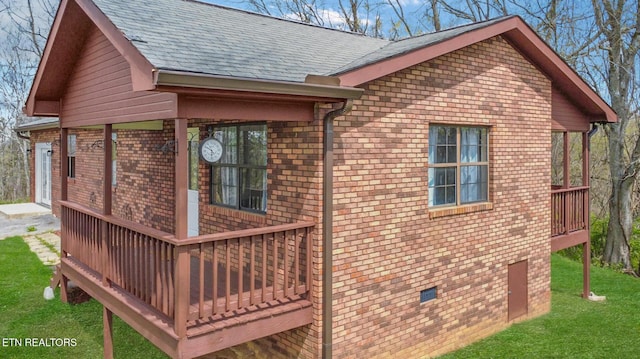 view of home's exterior with a yard, a shingled roof, and brick siding