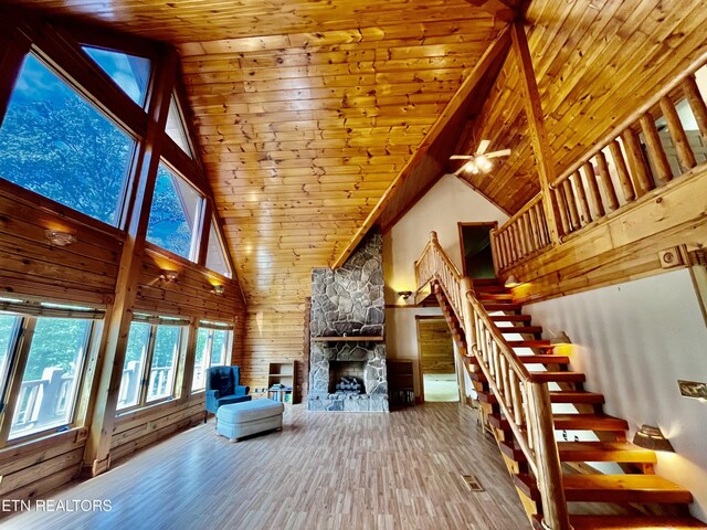 unfurnished living room featuring high vaulted ceiling, a fireplace, wooden ceiling, wood-type flooring, and ceiling fan