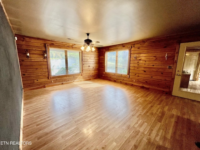 spare room featuring a ceiling fan, wood finished floors, and wooden walls