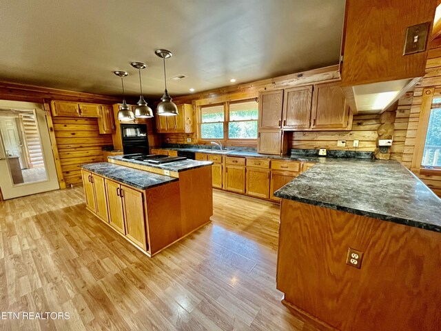 kitchen with decorative light fixtures, light wood-type flooring, wood walls, and a kitchen island