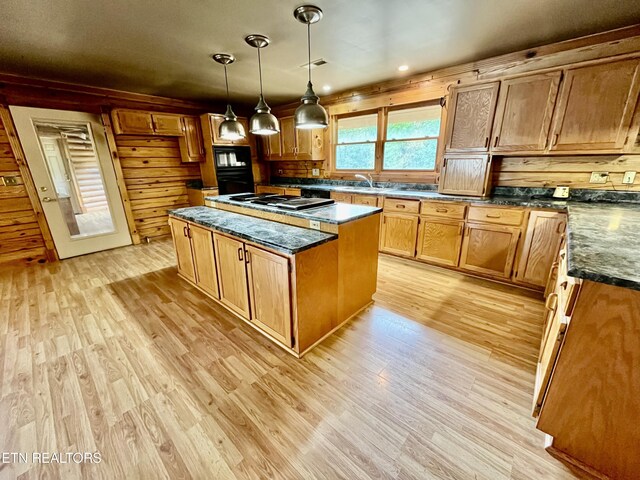 kitchen featuring wooden walls, a kitchen island, light hardwood / wood-style flooring, and decorative light fixtures