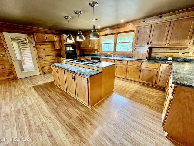 kitchen featuring a sink, light wood-type flooring, brown cabinetry, a kitchen island, and hanging light fixtures