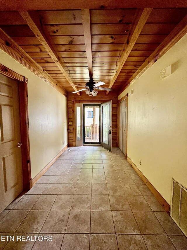 empty room featuring ceiling fan, light tile patterned floors, beam ceiling, and wooden ceiling