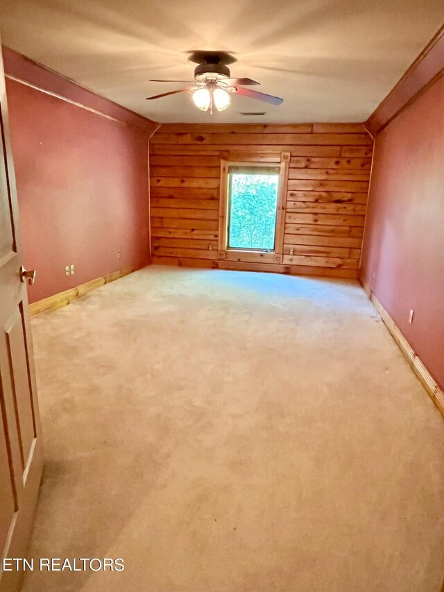 unfurnished room with ceiling fan, wood walls, and carpet flooring