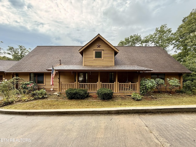 view of front of home with faux log siding, a porch, and a shingled roof