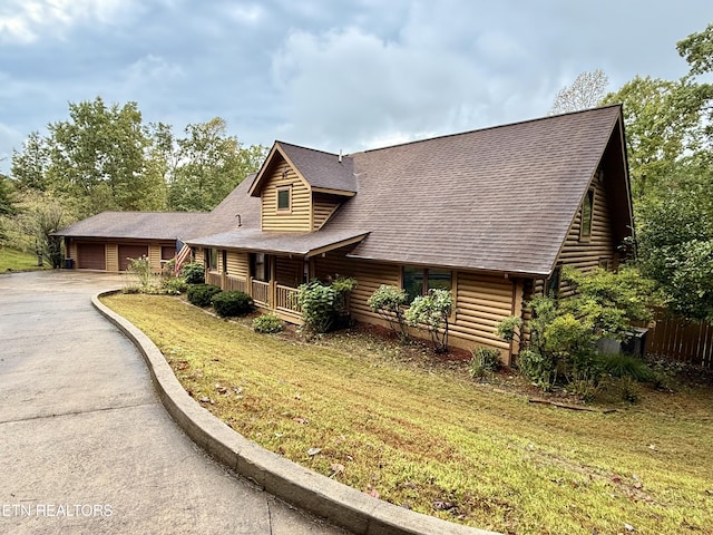 view of front facade with a front yard, driveway, roof with shingles, and log exterior