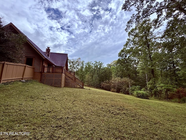 view of yard with a wooden deck, stairway, and fence