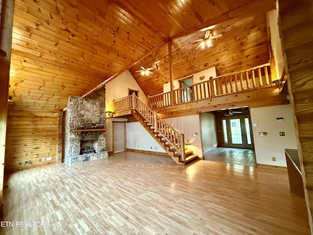 unfurnished living room with wood ceiling, a ceiling fan, high vaulted ceiling, and stairs