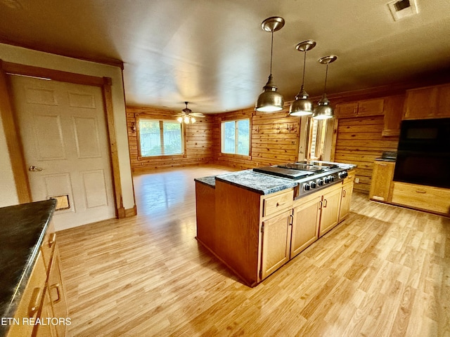 kitchen with black appliances, ceiling fan, wooden walls, and light wood-type flooring