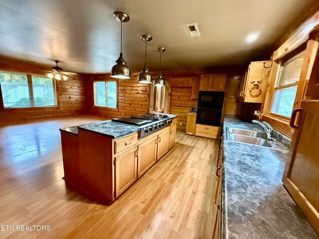 kitchen with wooden walls, ceiling fan, pendant lighting, and plenty of natural light