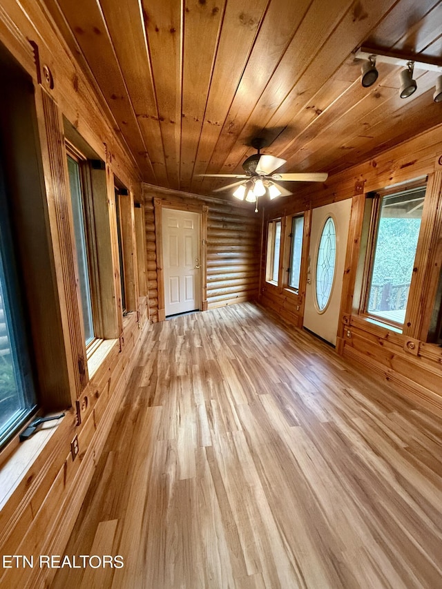 interior space featuring wooden ceiling, rustic walls, a ceiling fan, and light wood finished floors