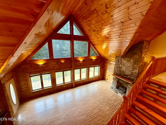 unfurnished living room featuring light hardwood / wood-style floors, wood ceiling, a fireplace, and vaulted ceiling