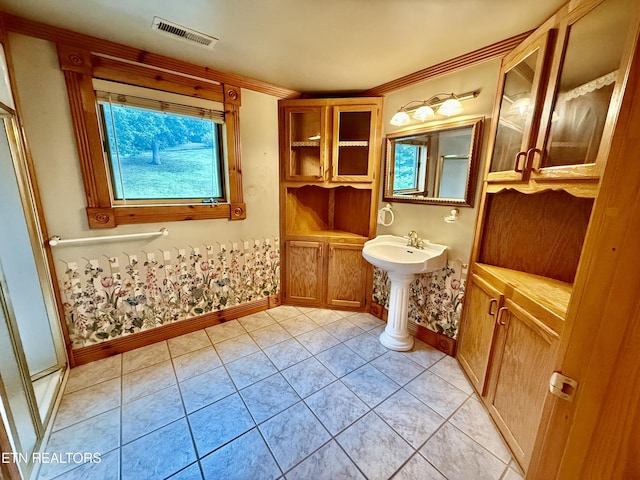 bathroom with a sink, baseboards, visible vents, a shower with door, and tile patterned flooring