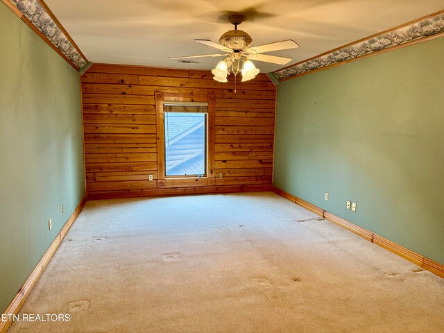 carpeted spare room featuring wooden walls, lofted ceiling, ceiling fan, and crown molding