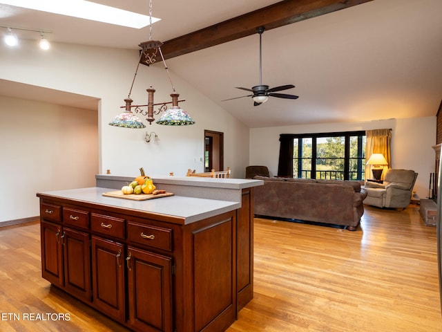 kitchen with ceiling fan, vaulted ceiling with beams, light hardwood / wood-style floors, and a kitchen island