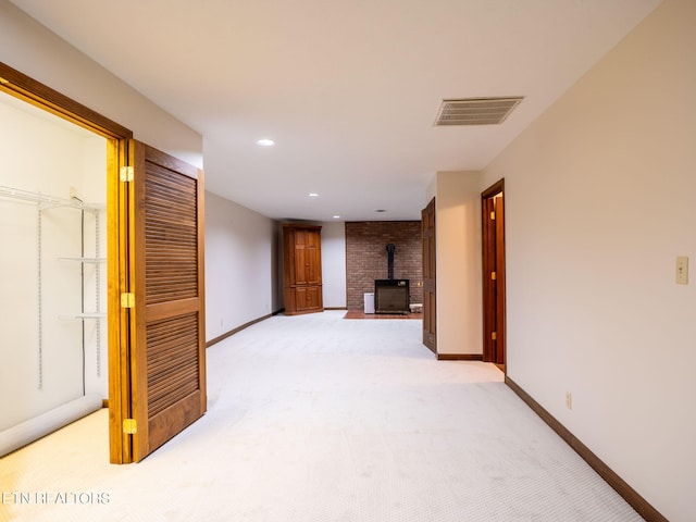 unfurnished living room featuring light colored carpet and a wood stove