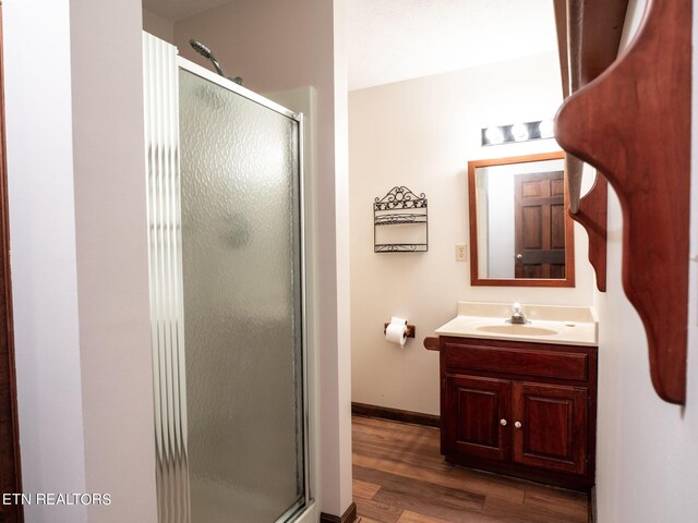 bathroom featuring wood-type flooring, a shower with door, and vanity