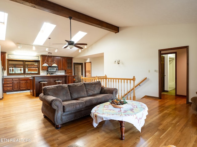 living room featuring ceiling fan, a skylight, beam ceiling, high vaulted ceiling, and hardwood / wood-style flooring