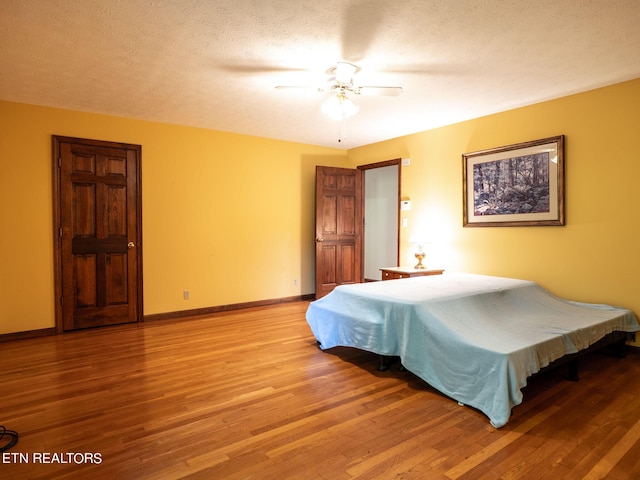 bedroom with light wood-style floors, baseboards, a ceiling fan, and a textured ceiling