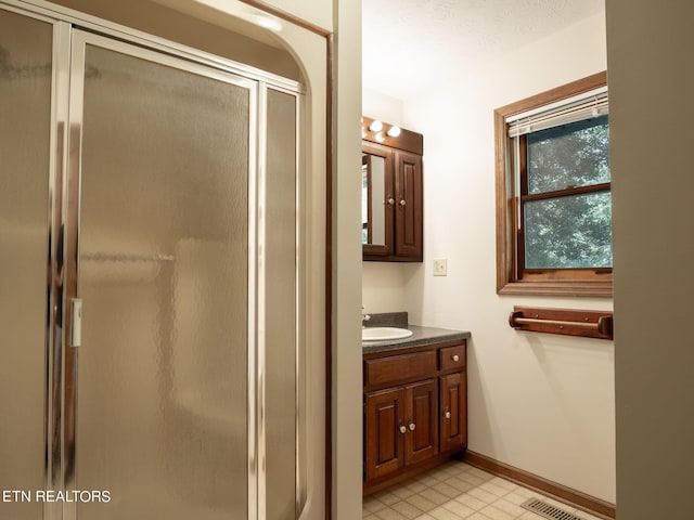 bathroom featuring vanity, visible vents, baseboards, tile patterned floors, and a shower stall