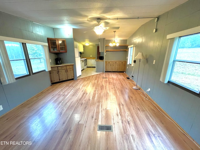 unfurnished living room featuring lofted ceiling, plenty of natural light, a notable chandelier, and light wood-type flooring