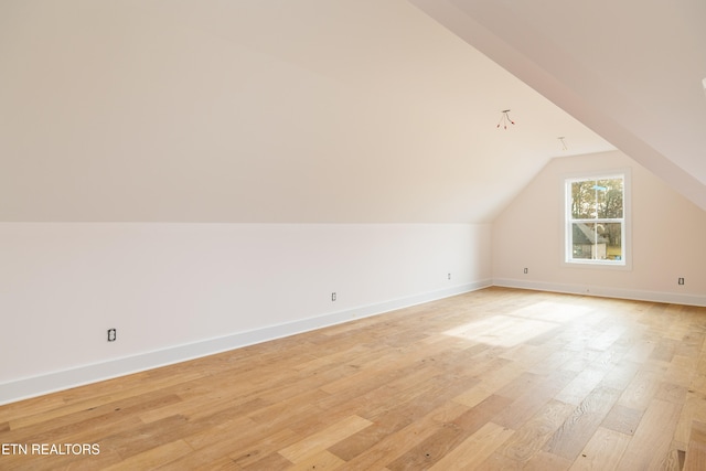 additional living space with light hardwood / wood-style flooring and lofted ceiling