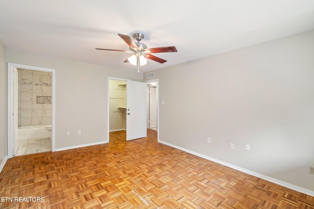 unfurnished bedroom with light parquet floors, ensuite bath, ceiling fan, and a walk in closet