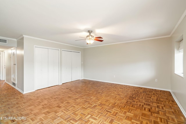 unfurnished bedroom featuring light parquet flooring, ornamental molding, two closets, and ceiling fan