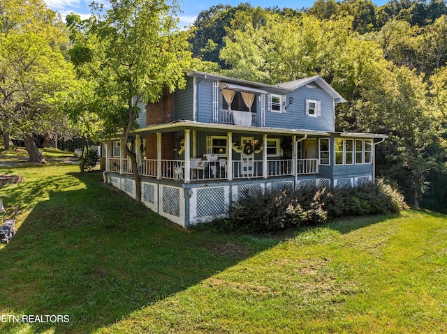 back of property featuring a sunroom, brick siding, a porch, and a lawn