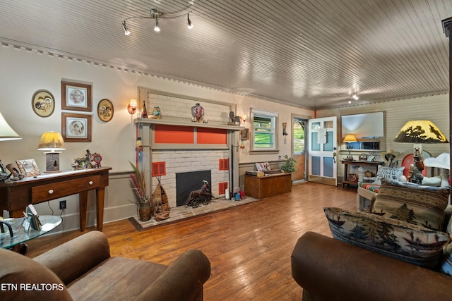 living area featuring wood finished floors, track lighting, and a brick fireplace