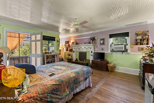 bedroom featuring crown molding, hardwood / wood-style flooring, baseboards, a fireplace with raised hearth, and cooling unit
