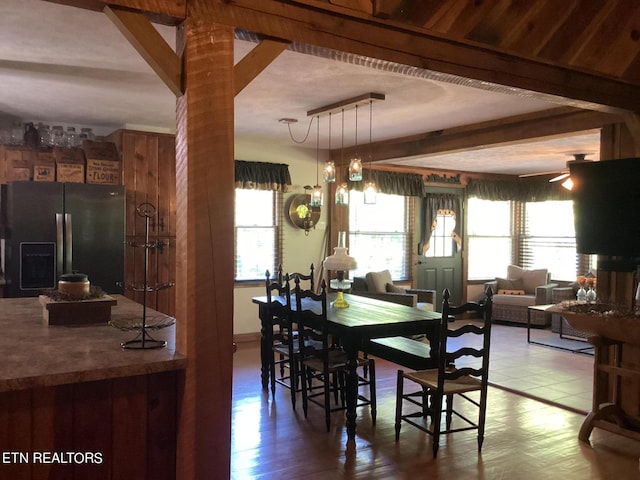 dining room with wood-type flooring, wooden walls, and ceiling fan