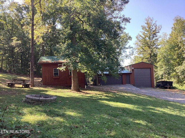 view of yard with an outdoor structure, gravel driveway, and a fire pit