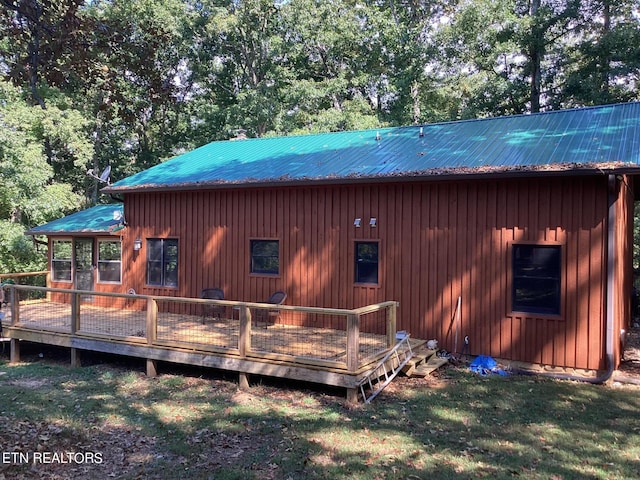 rear view of house featuring a lawn, metal roof, and a wooden deck