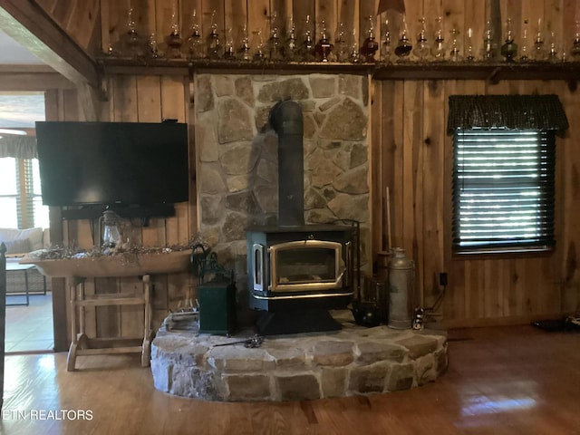 details featuring hardwood / wood-style flooring, wood walls, and a wood stove