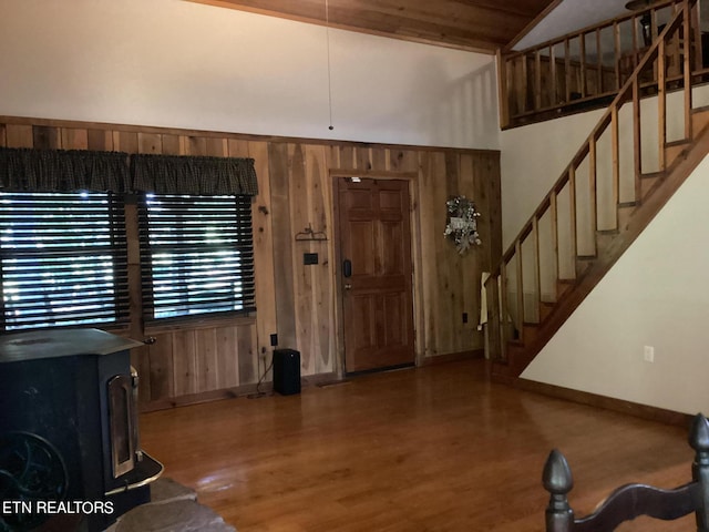 entryway with hardwood / wood-style flooring, wooden walls, a wood stove, and lofted ceiling