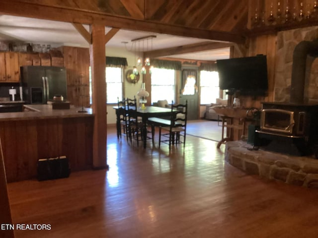 kitchen with open floor plan, stainless steel fridge, beam ceiling, and wood finished floors