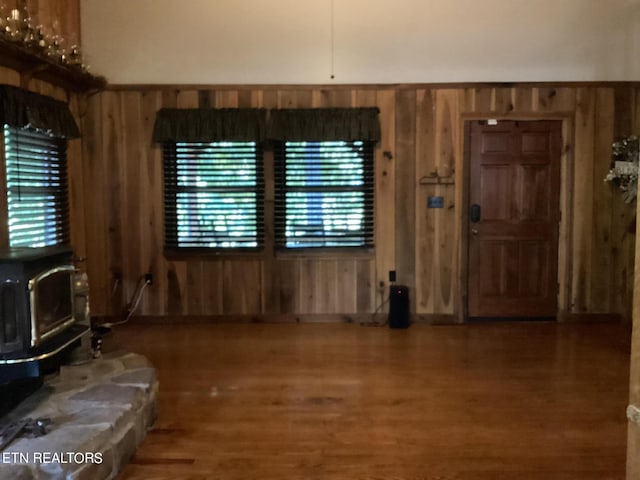 living room with a wood stove, wood walls, and hardwood / wood-style flooring