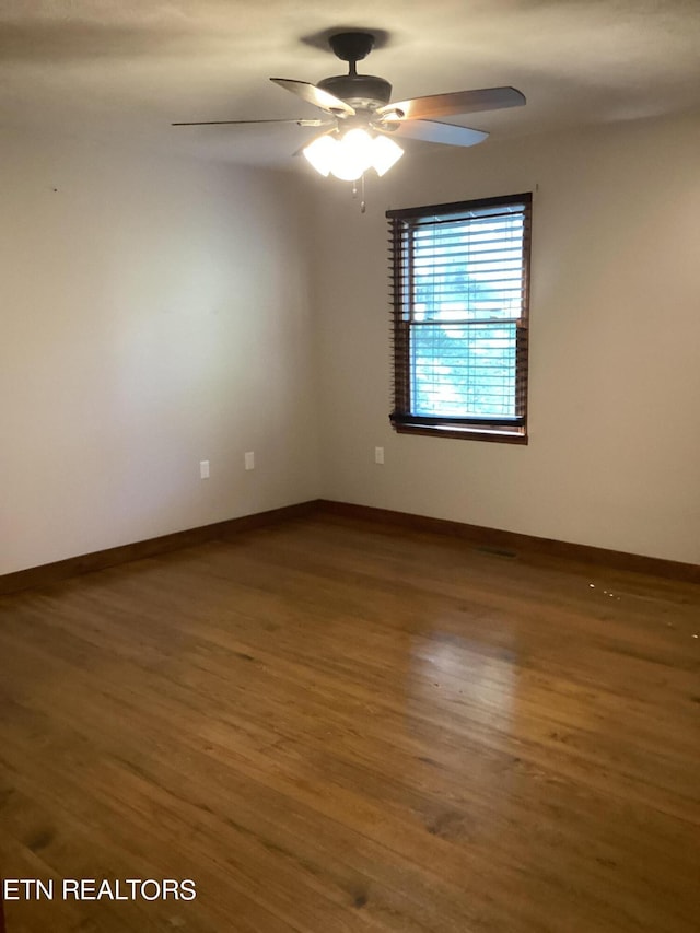 empty room featuring baseboards, wood finished floors, and a ceiling fan